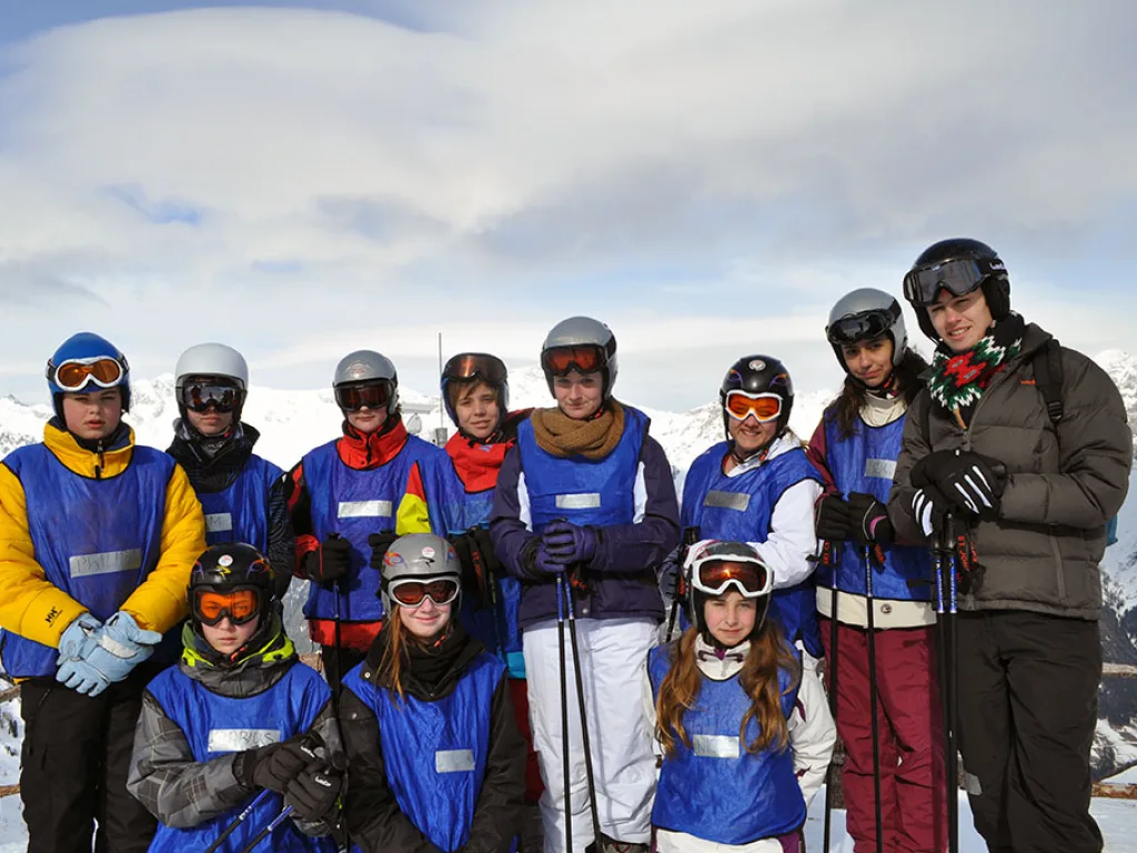Gruppenfoto auf der Piste, alle tragen Helm und Skibrille.